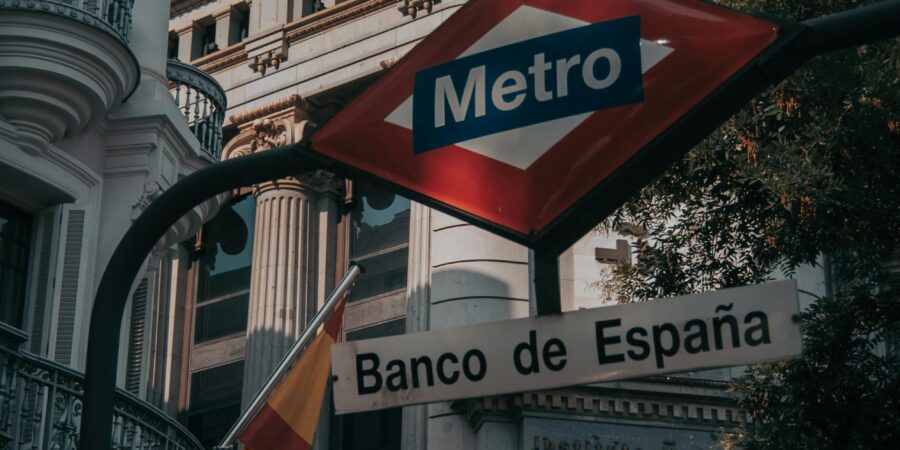 Urban view of Madrid's Banco de España with metro sign in the foreground, capturing city life.